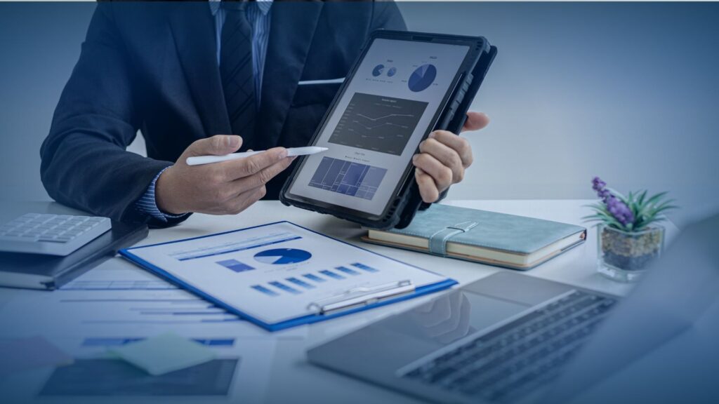 A professional in a suit holding a tablet showing growth analytics and an msp lead generation strategy at a modern desk.